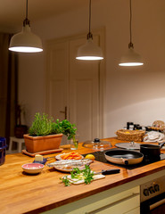 Küche mit Holz Arbeitsplatte, frische Zutaten für das Abendessen neben dem Herd, Fische, Möhren, Kräuter, Butter, Zitrone