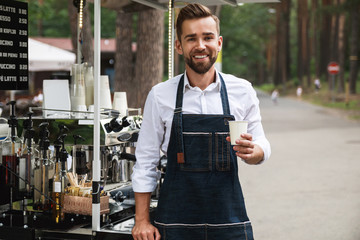 Handsome barista man during work in his street coffee shop