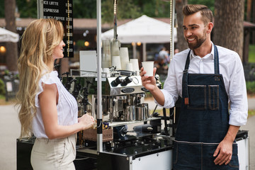 Barista man giving cup of coffee to woman customer