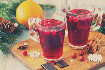Christmas, Thanksgiving drinks. Hot winter drink with cranberries and cinnamon on wooden table. Toned image.