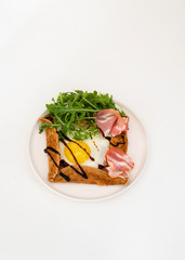 Galette bretonne  with fried eggs, arugula and bacon.