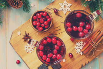 Christmas, Thanksgiving drinks. Hot winter drink with cranberries and cinnamon on wooden table. Top view flat lay. Toned image.