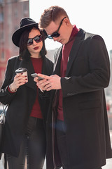 young beautiful woman and young handsome man in black glasses look at the phone