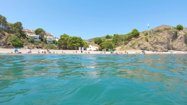 Spain Costa Brava, beach coastline in summer seen from water surface and moving camera down underwater, Colera bay, Mediterranean sea, Catalonia