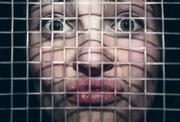 Naklejka premium Portrait of a frustrated young woman behind the lattice of a tennis racket