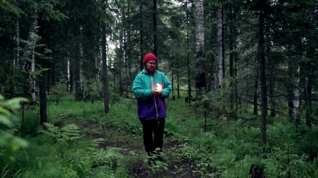 Man with colored smoke bombs in nature. Stock footage. Young man set fire to smoke bombs and they sparkled before smoke in forest