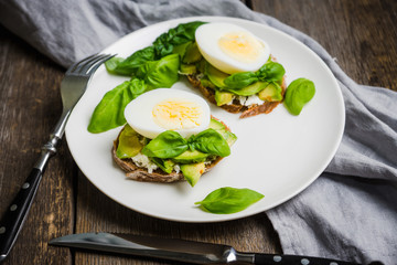 Sandwich with avocado, egg, cheese and basil leaves. Selective focus. Shallow depth of field.