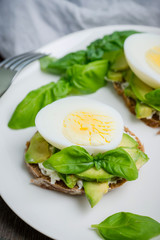 Sandwich with avocado, egg, cheese and basil leaves. Selective focus. Shallow depth of field.