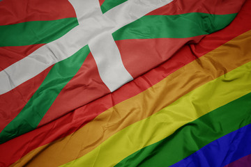 waving colorful gay rainbow flag and national flag of basque country.
