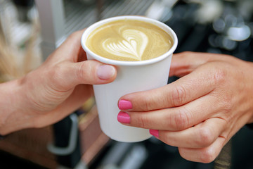 Barista giving to the customer paper cup with cappuccino