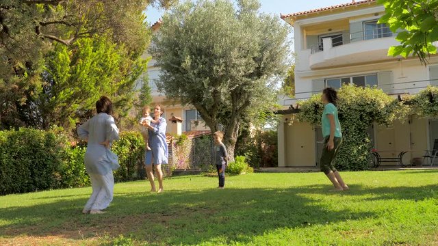 Happy family having fun while doing sports in slow motion on front yard of luxury house, villa. Summer holidays concept. Summer vacation with family, Healthy recreations and sports on fresh air