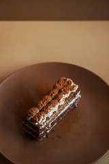 Tiramisu cake on brown background. Minimal modern dessert concept
