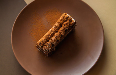 Tiramisu cake on brown background. Minimal modern dessert concept. Top view