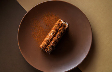 Tiramisu cake on brown background. Minimal modern dessert concept. Top view