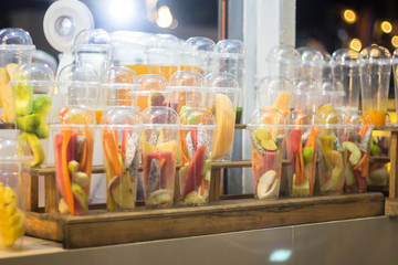 Different kinds of fruits in plastic glasses for making smoothies.