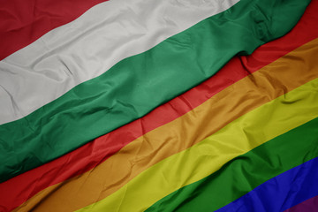 waving colorful gay rainbow flag and national flag of hungary.