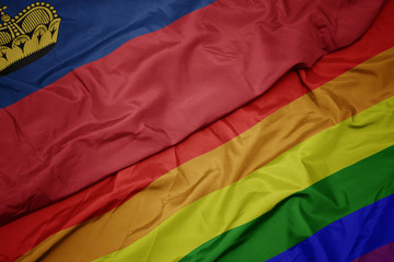 waving colorful gay rainbow flag and national flag of liechtenstein.