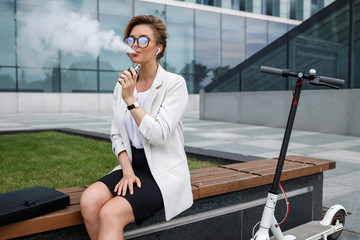 Young businesswoman  smoking vape after her work