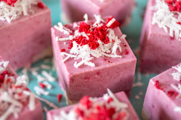 Delicious raw vegan volcano cakes from fermented cashew mousse, with raspberry jam lava, decorated with coconut flakes and sublimated raspberries. Gluten-free, no eggs. Healthy eating concept.