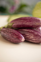 Closeup view of small purple Asian eggplants, food background photography. Pile of fresh eggplants at Indian market, vegetarian food. Above small Asian purple eggplants, ecology and nature concept