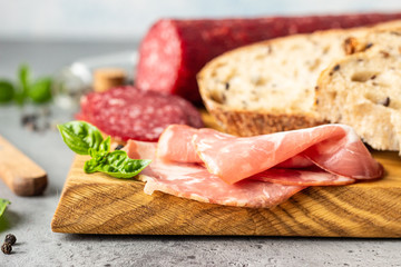 Traditional artisan bread with seeds and pork sausage and salami served on a wooden cutting board. Open sandwich with pork sausage.