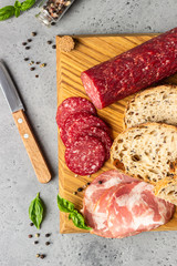 Traditional artisan bread with seeds and pork sausage and salami served on a wooden cutting board. Open sandwich with pork sausage.