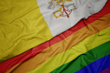 waving colorful gay rainbow flag and national flag of vatican city.