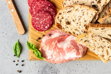 Traditional artisan bread with seeds and pork sausage and salami served on a wooden cutting board. Open sandwich with pork sausage.