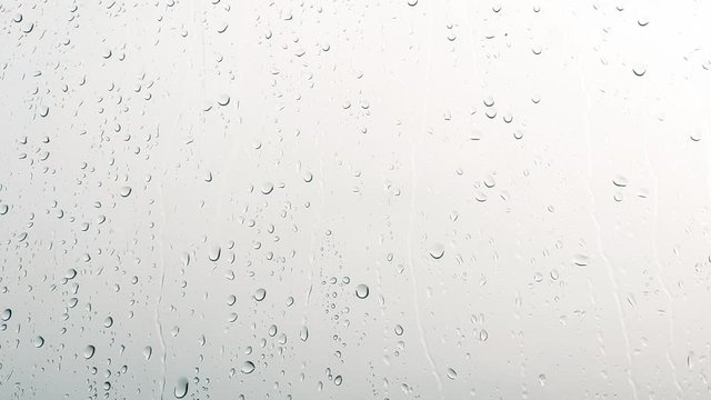 Close-up of water droplets on glass, Rain Rain, Go Away. Large rain drops strike a window pane
