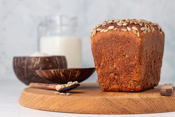 Loaf of wholegrain rye bread with seeds on a wooden cutting board.