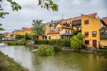 Fototapeta premium a picturesque canal with bulrush along old yellow houses