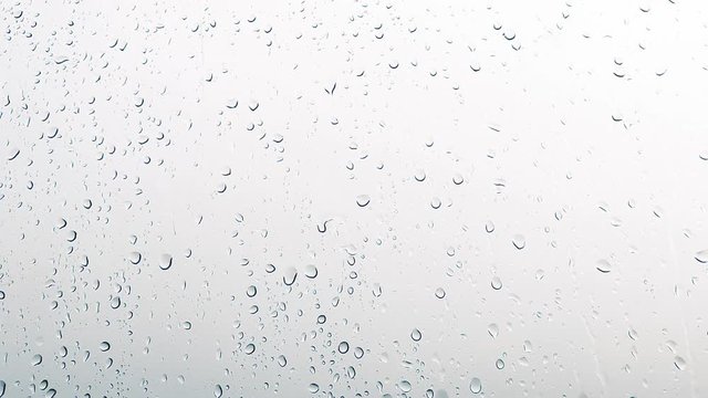 Close-up of water droplets on glass, Rain Rain, Go Away. Large rain drops strike a window pane