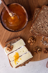 Sliced rye bread on cutting board with camembert cheese and honey. Whole grain rye bread with seeds. Breakfast.