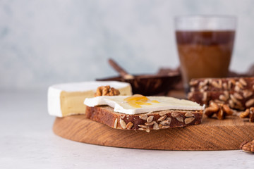 Sliced rye bread on cutting board with camembert cheese and honey. Whole grain rye bread with seeds. Breakfast.