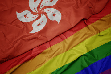 waving colorful gay rainbow flag and national flag of hong kong.