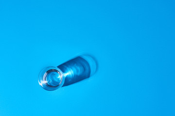 A glass filled with clear water on a blue background. Top view.