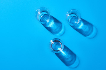 Three glasses with water on a blue background. Top view.