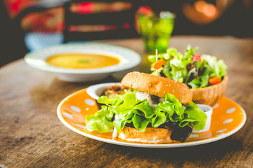 Home-made tofu burger carefully made of tofu and onion teriyaki sauce.small pan fried shredded potato and small salad and pumpkin soup