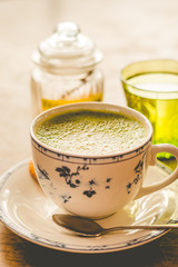 green tea matcha soy latte in a china cup with brown sugar and a glass of water on the side