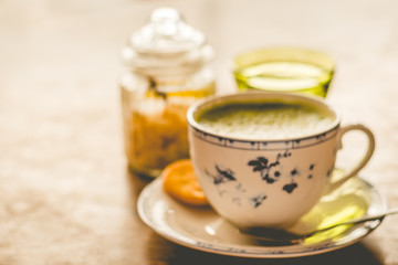green tea matcha soy latte in a china cup with brown sugar and a glass of water on the side