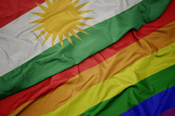 waving colorful gay rainbow flag and national flag of kurdistan.