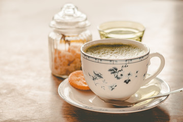 green tea matcha soy latte in a china cup with brown sugar and a glass of water on the side