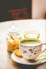 green tea matcha soy latte in a china cup with brown sugar and a glass of water on the side