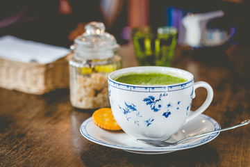 green tea matcha soy latte in a china cup with brown sugar and a glass of water on the side