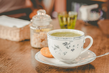 green tea matcha soy latte in a china cup with brown sugar and a glass of water on the side