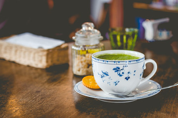 green tea matcha soy latte in a china cup with brown sugar and a glass of water on the side