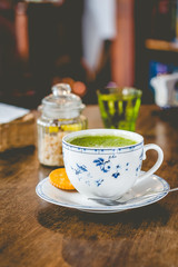 green tea matcha soy latte in a china cup with brown sugar and a glass of water on the side