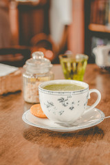 green tea matcha soy latte in a china cup with brown sugar and a glass of water on the side