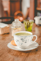 green tea matcha soy latte in a china cup with brown sugar and a glass of water on the side