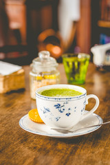 green tea matcha soy latte in a china cup with brown sugar and a glass of water on the side